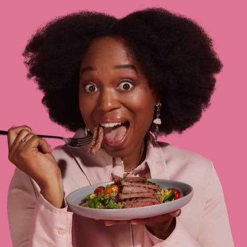 Happy woman eating beef and vegetables