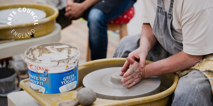 A person at a potters wheel, making something out of clay. 