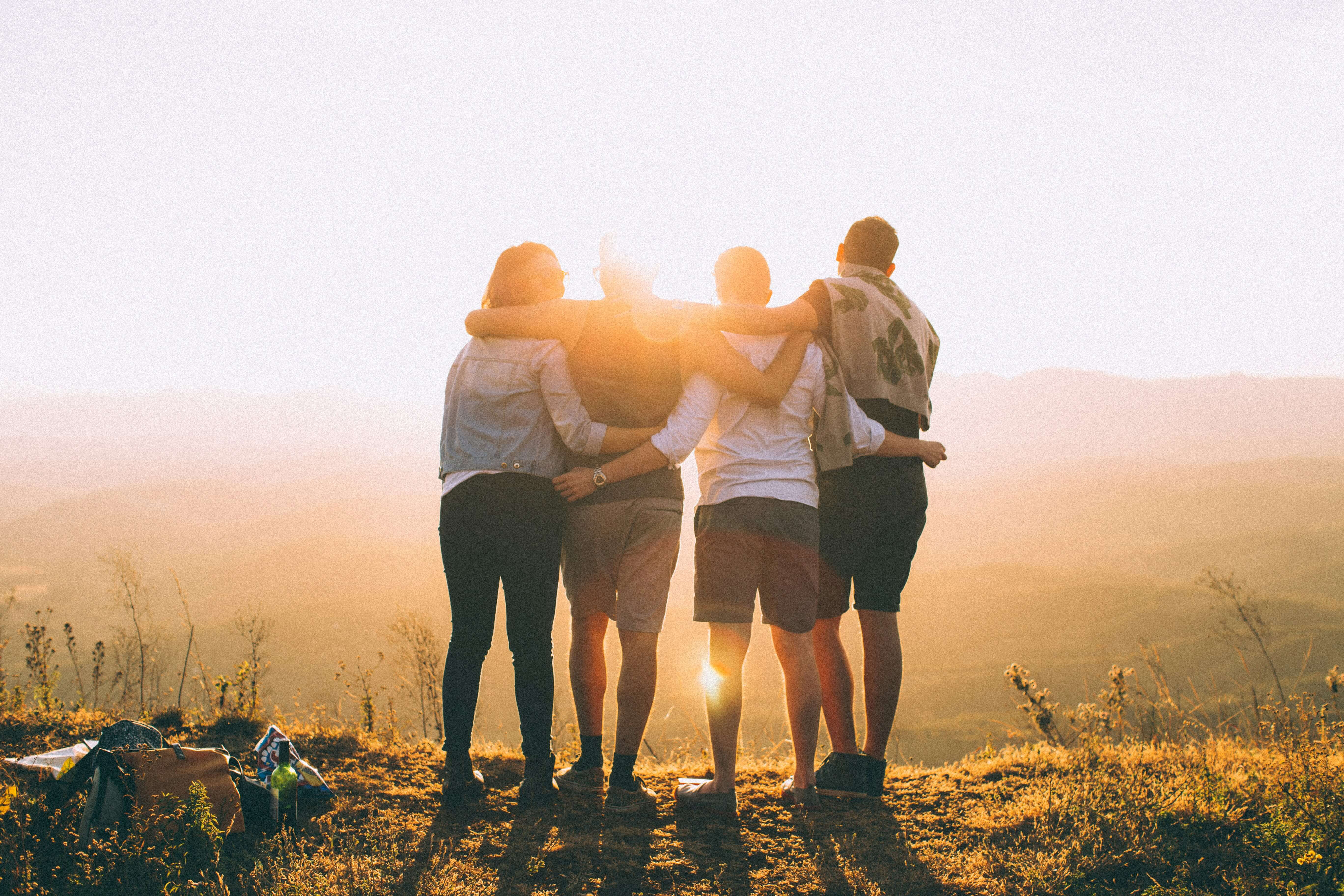 Group of friends hugging looking over a mountain view