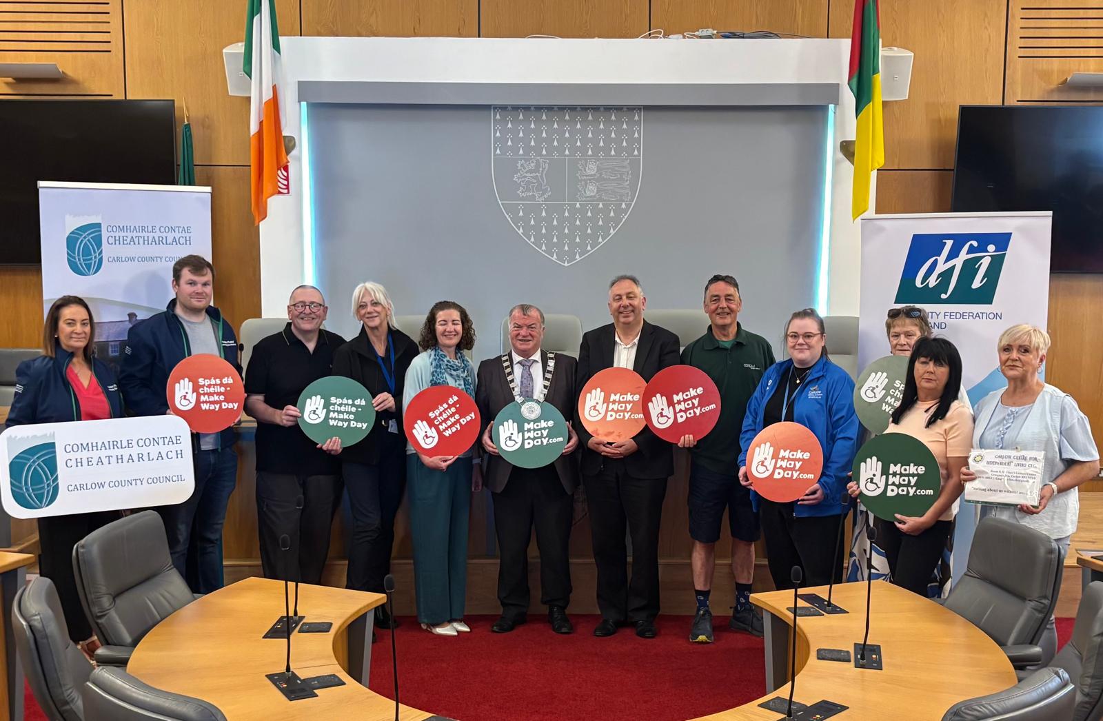 A group of people posing in a council chamber holding 