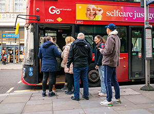 a queue of people waiting to get onto a London bus